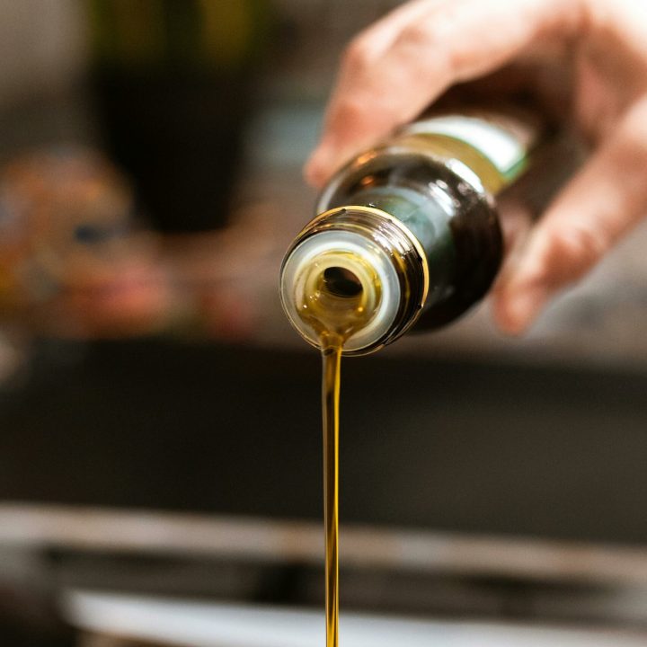 A close-up shot of olive oil being poured into a pan, highlighting healthy cooking.